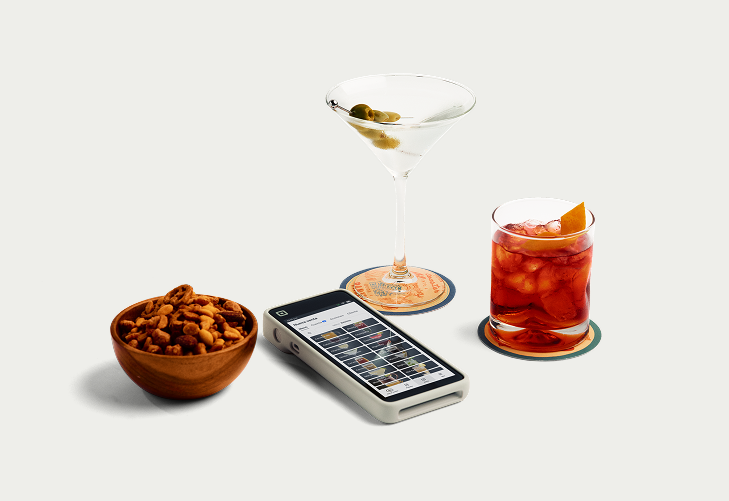 Square Terminal on bar surface with Nueva venta menu; martini, red cocktail, and snack bowl