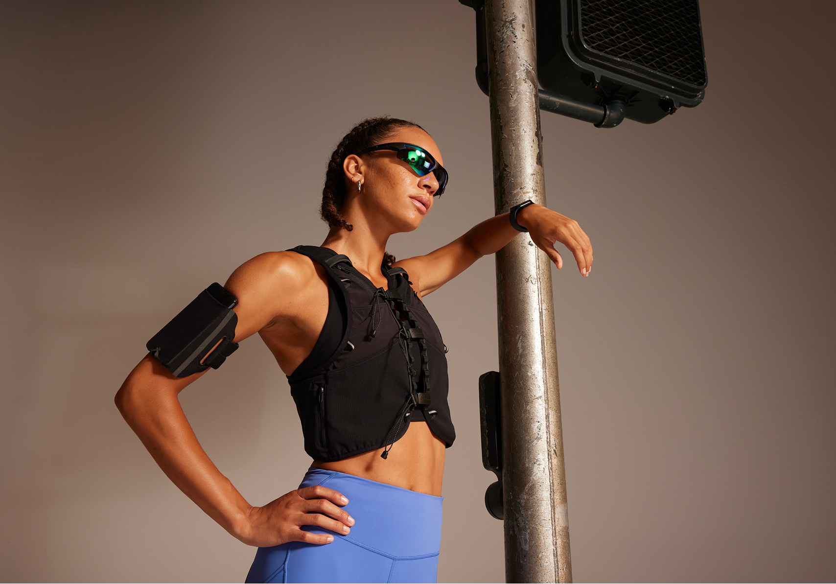 lululemon leggings and running vest — model with urban pole prop, blue tights, armband and sunglasses on neutral studio background